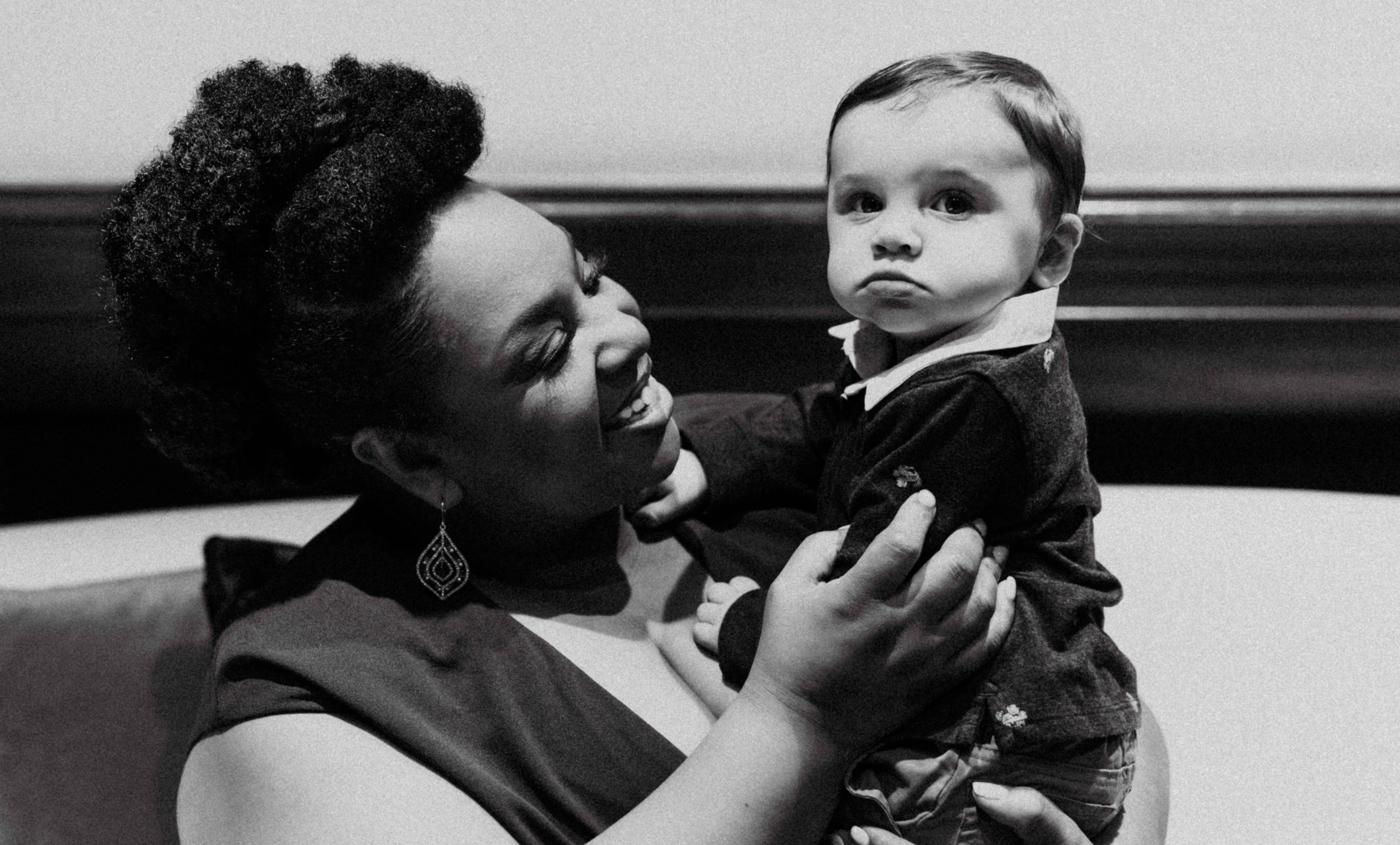 Tamika Felder, a cervical cancer advocate and motivational speaker, holds her son, Chayton, during a quiet moment at a NYC event. He is sleeping in her arms with a pacifier in his mouth.