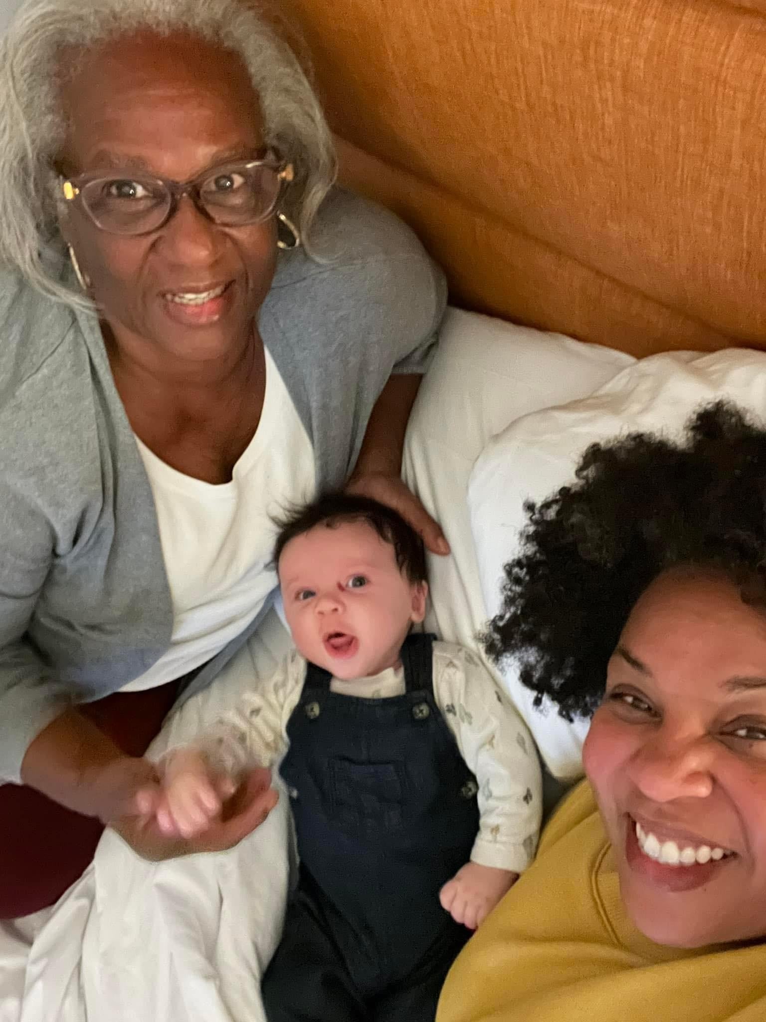 Tamika Felder, her son Chayton, and her late sister Valildra smile together on a bed.