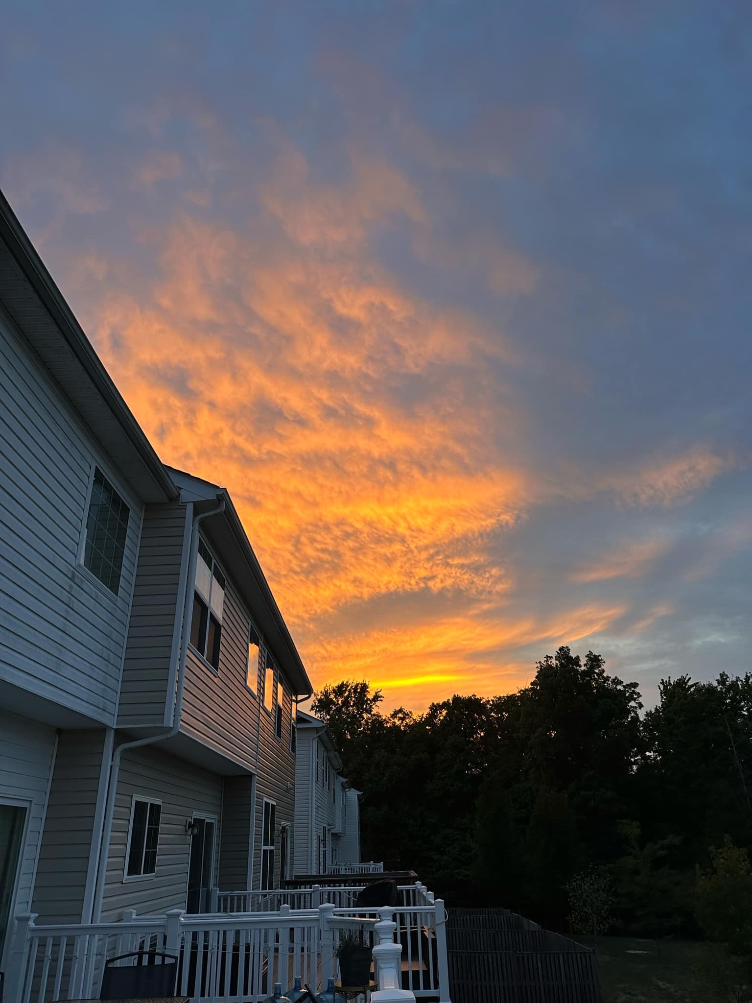 A stunning sunset viewed from the back of Tamika Felder's house. The sky is filled with vibrant hues of orange, pink, and purple, casting a warm glow over the surrounding landscape.