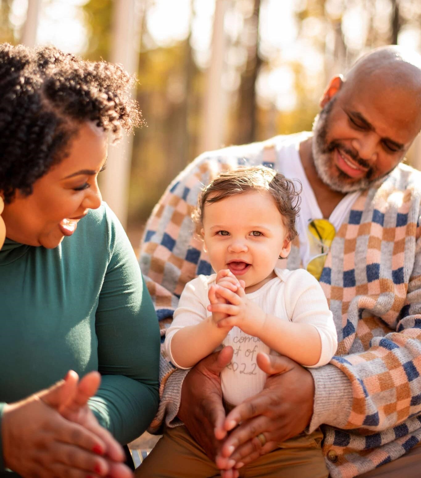 Tamika Felder, her husband Rocky Campbell, and their son Chayton, the original Cervivor Baby, smile together outside during the fall. The family enjoys a warm moment surrounded by autumn foliage.